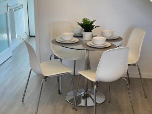 a dining room table with white chairs and a table with cups at High Tide House in Christchurch