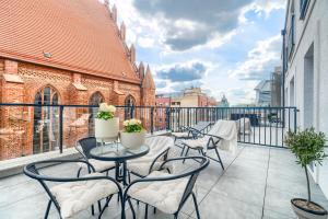eine Terrasse mit Tischen und Stühlen auf dem Balkon in der Unterkunft Apartament 1000 Stare Miasto Apartamenty No.1 in Stettin