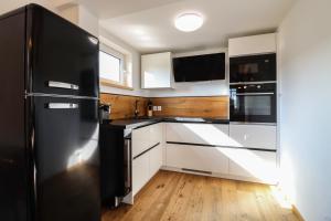 cocina con nevera negra y armarios blancos en WOOD HOME - Luxury Mountain Apartment en Horní Malá Úpa