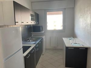 La cuisine est équipée d'un évier et d'un réfrigérateur blanc. dans l'établissement Appartement 6 places à 200m de l'océan, à La Rochelle