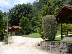 um caminho que leva a uma casa com um arbusto em Pousada Ypê das Montanhas em Monte Alegre do Sul