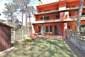 ein orangenes Haus mit einem Zaun und einem Hof in der Unterkunft Apartamento, praia, golfe, Lisboa piscina publica com terifa in Almada