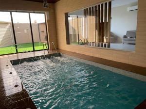 a swimming pool in a house with a large window at شاليهات ارينا الفندقية بالطائف in Ash Shuwaybiţ