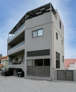 un grand bâtiment avec une voiture garée dans un parking dans l'établissement Apartment Lazarous 3, à Apolakkiá