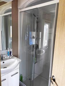 a bathroom with a glass shower and a sink at bracken lodge in Chapel Saint Leonards