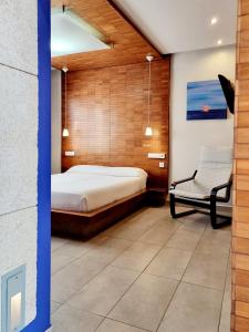 a bedroom with a bed and a chair at Apartamentos El Arrecife in Conil de la Frontera