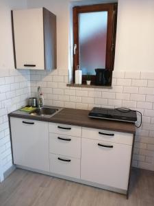a kitchen with white cabinets and a sink and a window at Apartma Pinea in Portorož