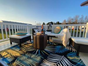 eine Terrasse mit einem Tisch, Stühlen und einem Teppich in der Unterkunft Prestige caravan,Seton Sands holiday village, WiFi in Port Seton