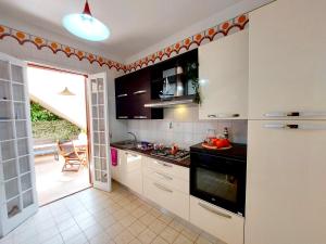 a kitchen with white cabinets and a stove top oven at CapoSud - Appartamento Giglio in Punta Secca