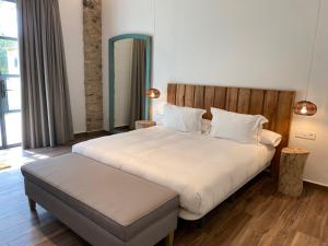 a bedroom with a large white bed with a wooden headboard at HOTEL MAS ARET in Peralada