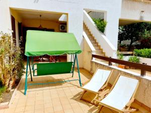 two chairs and a green umbrella on a patio at CapoSud - Appartamento Giglio in Punta Secca