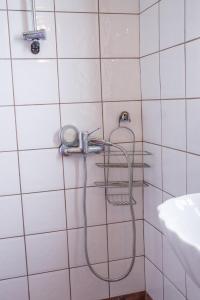 a shower in a white tiled bathroom with a hose at Sunray Luxury Apartment Zagora with piano in Zagora