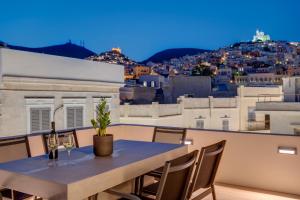 a table on a balcony with a view of a city at The Heart of Syra - Your Home in Ermoupolis in Ermoupoli