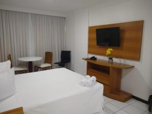 a hotel room with a bed and a flat screen tv at PONTA NEGRA FLAT APART in Natal