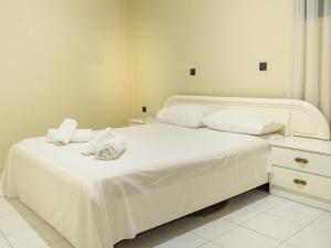 1 dormitorio con 2 camas, sábanas blancas y toallas en Apartment Lazarous 1, en Apolakkiá