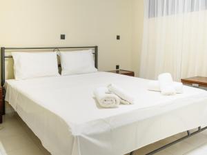 ein großes weißes Bett mit weißen Handtüchern darauf in der Unterkunft Apartment Lazarous 1 in Apolakkiá