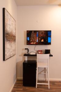 a desk with a white chair and a television on a wall at Golden Suite Bahai's Garden in Haifa