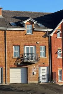 a brick building with a garage and a balcony at Luxury Portrush Holiday Homes - The Glynn, Portrush Sleeps 12 - 5 bedrooms in Portrush