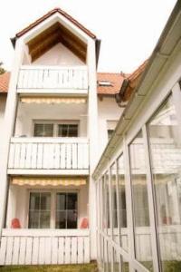 a white house with a porch and a balcony at Kurhotel Kaiser in Bad Wörishofen