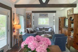a living room with a couch and a table with pink flowers at Historic Biloxi Bay Cottage with Beautiful View in Ocean Springs