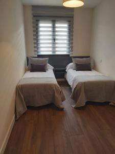 two beds in a small room with a window at CORRAL DEL DUQUE II in San Cristóbal de Segovia