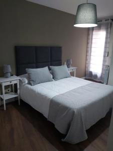 1 dormitorio con 1 cama blanca grande y 2 mesas en CORRAL DEL DUQUE II en San Cristóbal de Segovia