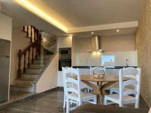 cocina y comedor con mesa de madera y sillas blancas en Apartamentos Currás en Touriñán, en Touriñán