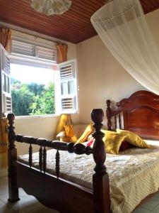 1 dormitorio con cama de madera y ventana en VILLA SIM et CILOTTE, en Le Marin