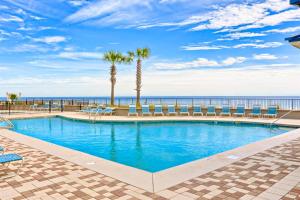 a swimming pool with chairs and the ocean in the background at Bluewater in Orange Beach