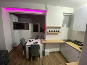 a small kitchen with a table and a pink light at The Location Central Town Apartament in Kragujevac