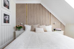 a white bedroom with a large white bed with white pillows at Gold Apartment Szczecinek in Szczecinek