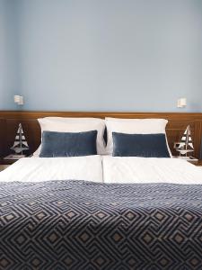 Cama con sábanas y almohadas azules y blancas en Vila Piranesi Apartments - Parking included, en Piran
