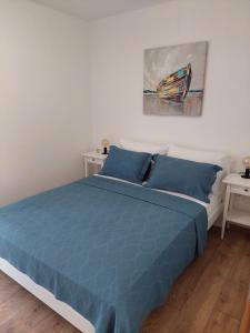 a bedroom with a blue bed and a painting on the wall at Bella Vista in Komarna