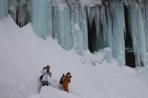 twee mensen staan in de sneeuw naast een ijsmuur bij Minpaku Taki - Vacation STAY 12842 in Gero