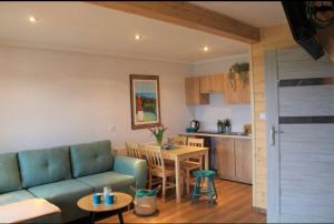 a living room with a blue couch and a kitchen at Morza szum in Karwia