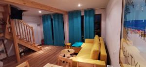 a living room with a yellow couch and blue curtains at Morza szum in Karwia