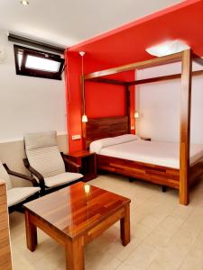 Habitación con 2 camas, sofá y mesa. en Apartamentos El Arrecife, en Conil de la Frontera