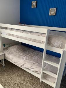 two white bunk beds in a room with a blue wall at Petite escapade à la Picardière in Fort-Mahon-Plage