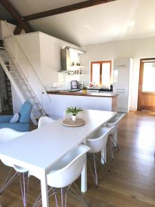 ein weißes Esszimmer mit einem weißen Tisch und Stühlen in der Unterkunft Le Mas de Coline in Rocamadour