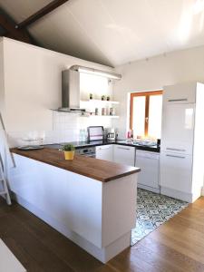 a kitchen with white cabinets and a wooden counter top at Le Mas de Coline in Rocamadour