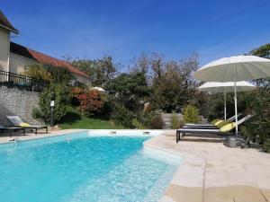 einen Pool mit einem Sonnenschirm und einer Bank in der Unterkunft Le Mas de Coline in Rocamadour