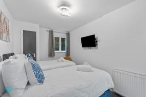 a bedroom with two beds and a tv on the wall at 4 Bed - Smeatons by Pureserviced in Plymouth
