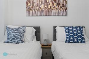 two beds in a bedroom with a picture on the wall at 4 Bed - Smeatons by Pureserviced in Plymouth