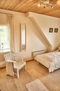 a bedroom with a bed and a chair and a window at Stylish vacation home - close to sea and nature in Hejls