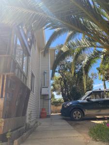 ein Auto, das vor einem Haus mit einer Palme parkt in der Unterkunft Deptos Guacolda in Algarrobo