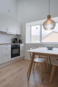 a white kitchen with a table and a dining room at Brand New / Airport / RentYourCar / Free Parking in Miðvágur