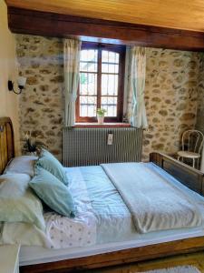 Cama grande en habitación con pared de piedra en Les Ecuries, traditional stone farmhouse with pool en Marquixanes
