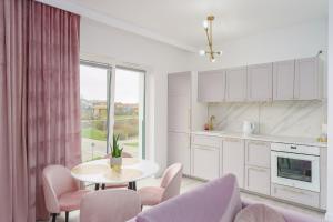 Biała kuchnia ze stołem i krzesłami oraz oknem w obiekcie Fredry 2 Apartament Liliowy w Kołobrzegu