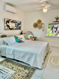 una camera con un grande letto bianco e un ventilatore di JaParaíso Pousada Ateliê a Japaratinga