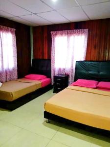 two beds in a room with pink sheets and windows at Ayah Perhentian in Perhentian Island